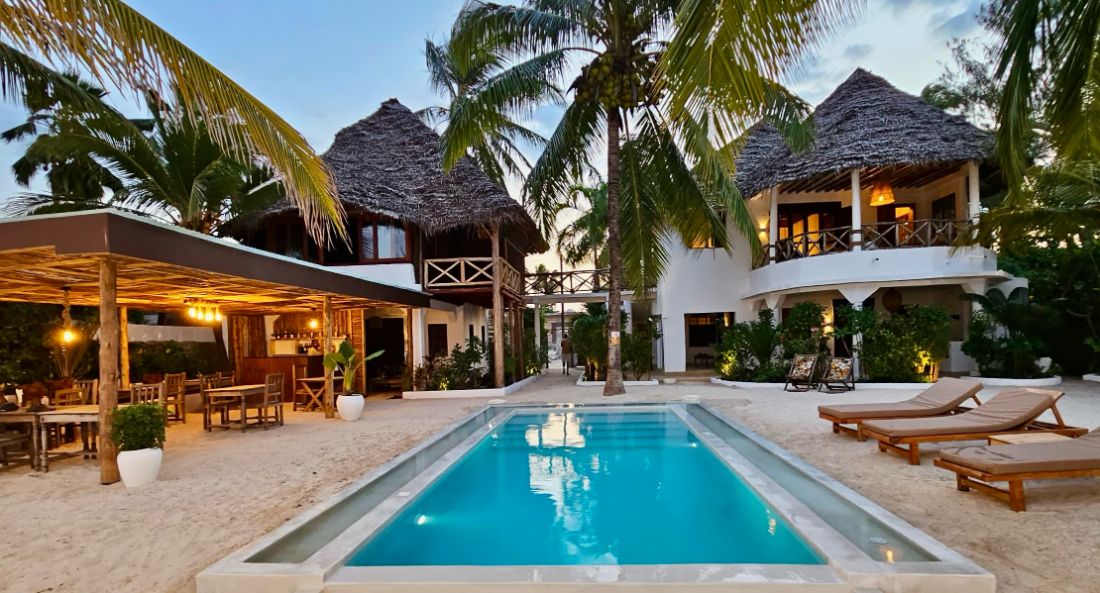 Pool and thatched villas at dusk